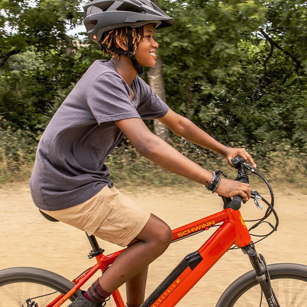 A kid smiling while riding a red Schwinn e-bike for kids.