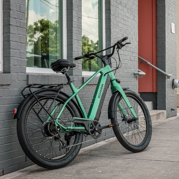 An emerald green Coston DX e-bike sitting against a wall.