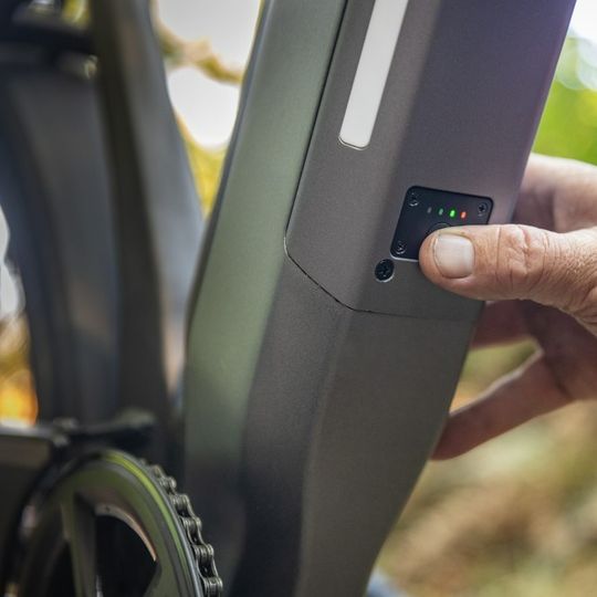 A hand pushing the power button on an electric bike to turn on the electric bike motor.