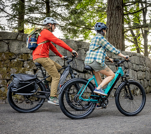 two people riding Schwinn Coston E-bikes through a wooded area